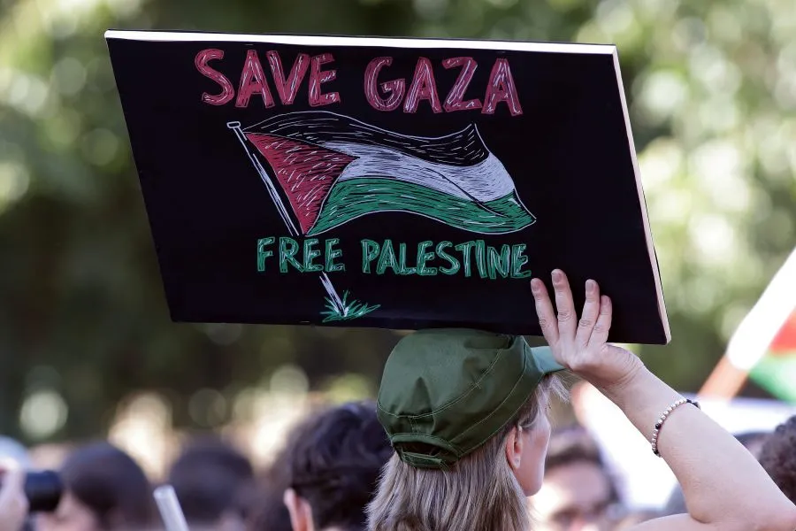 A girl holding a sign that says Save Gaza Free Palestine.